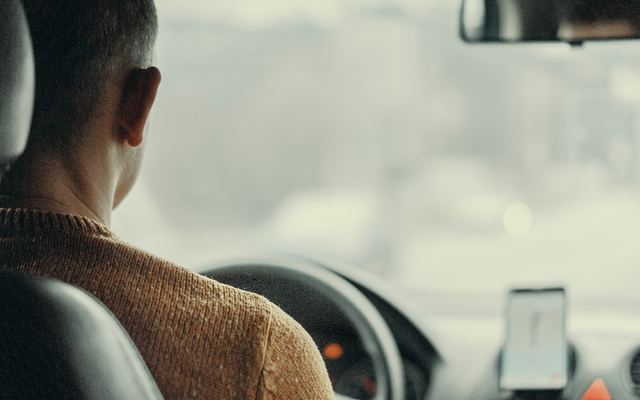 Een chauffeur aan het stuur, van achteren gezien