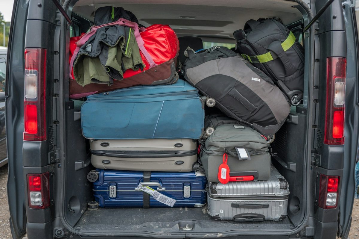 De open achterklep van een bestelwagen, volgeladen met tassen en koffers