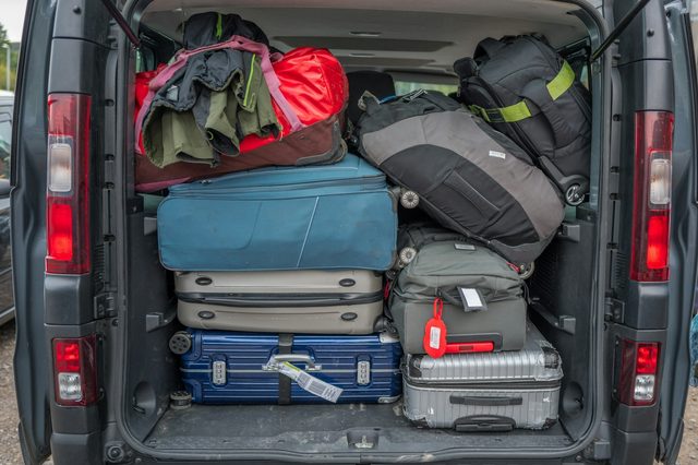 De open achterklep van een bestelwagen, volgeladen met koffers en reistassen
